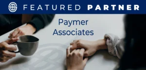 Image showing two people holding hands on a table, one also holding a mug, conveying comfort and support.